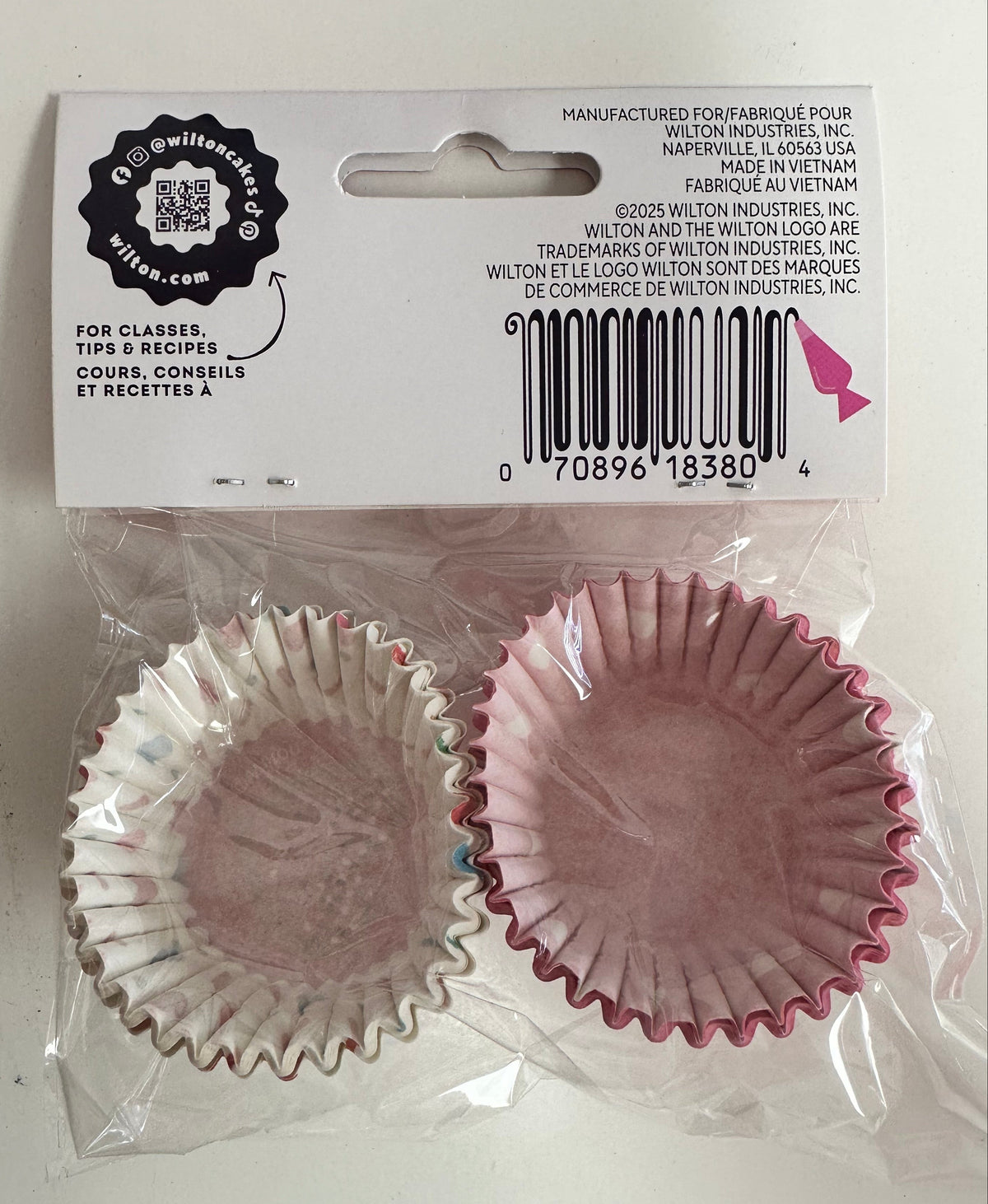 Pink cupcake liners in clear packaging with Wilton label on a white background