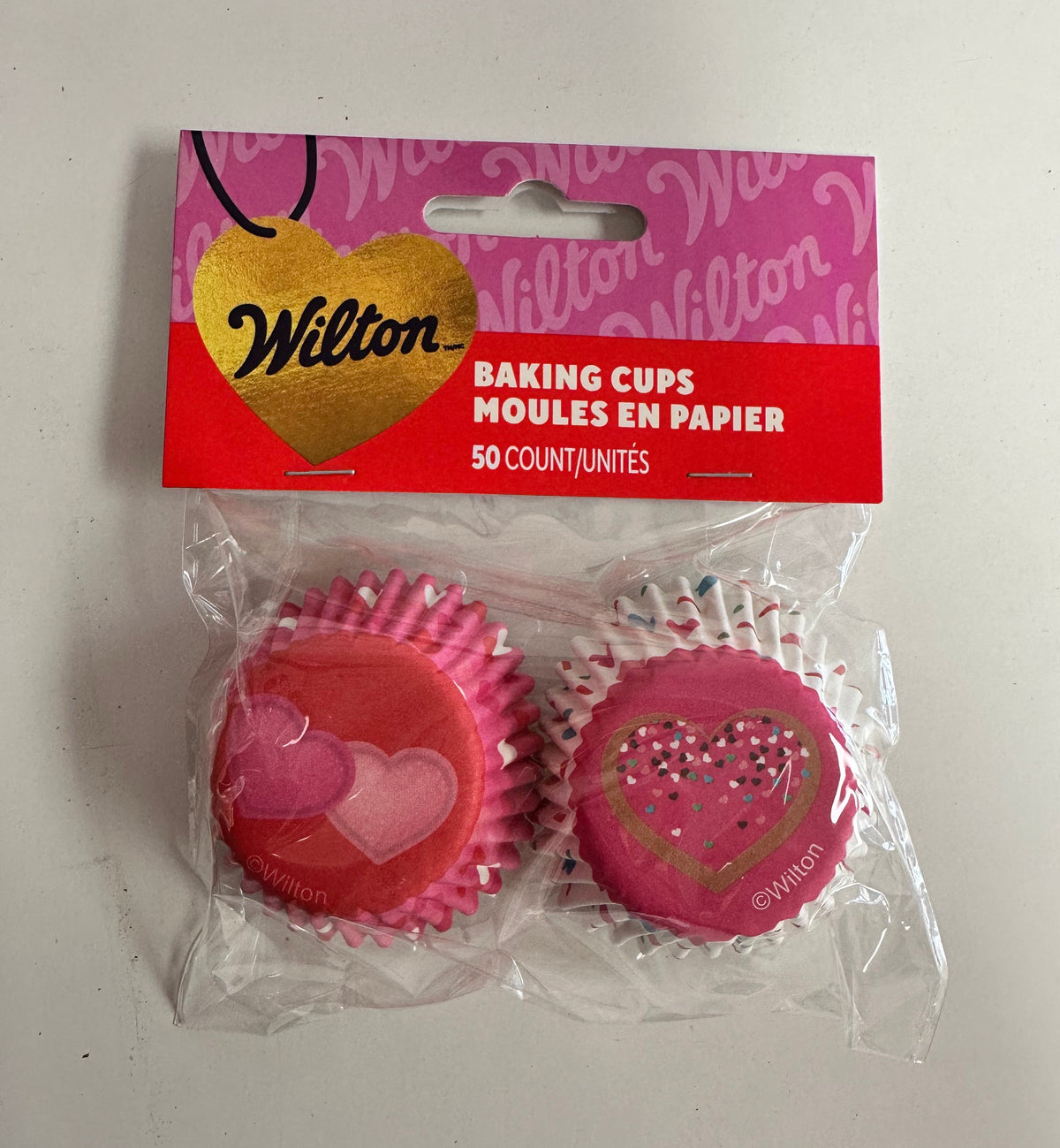 Pink baking cups with a Wilton box on a white background