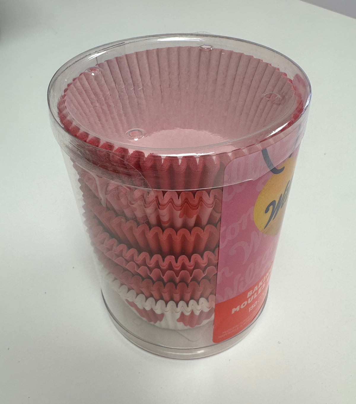Container of pink cupcake liners on a white surface